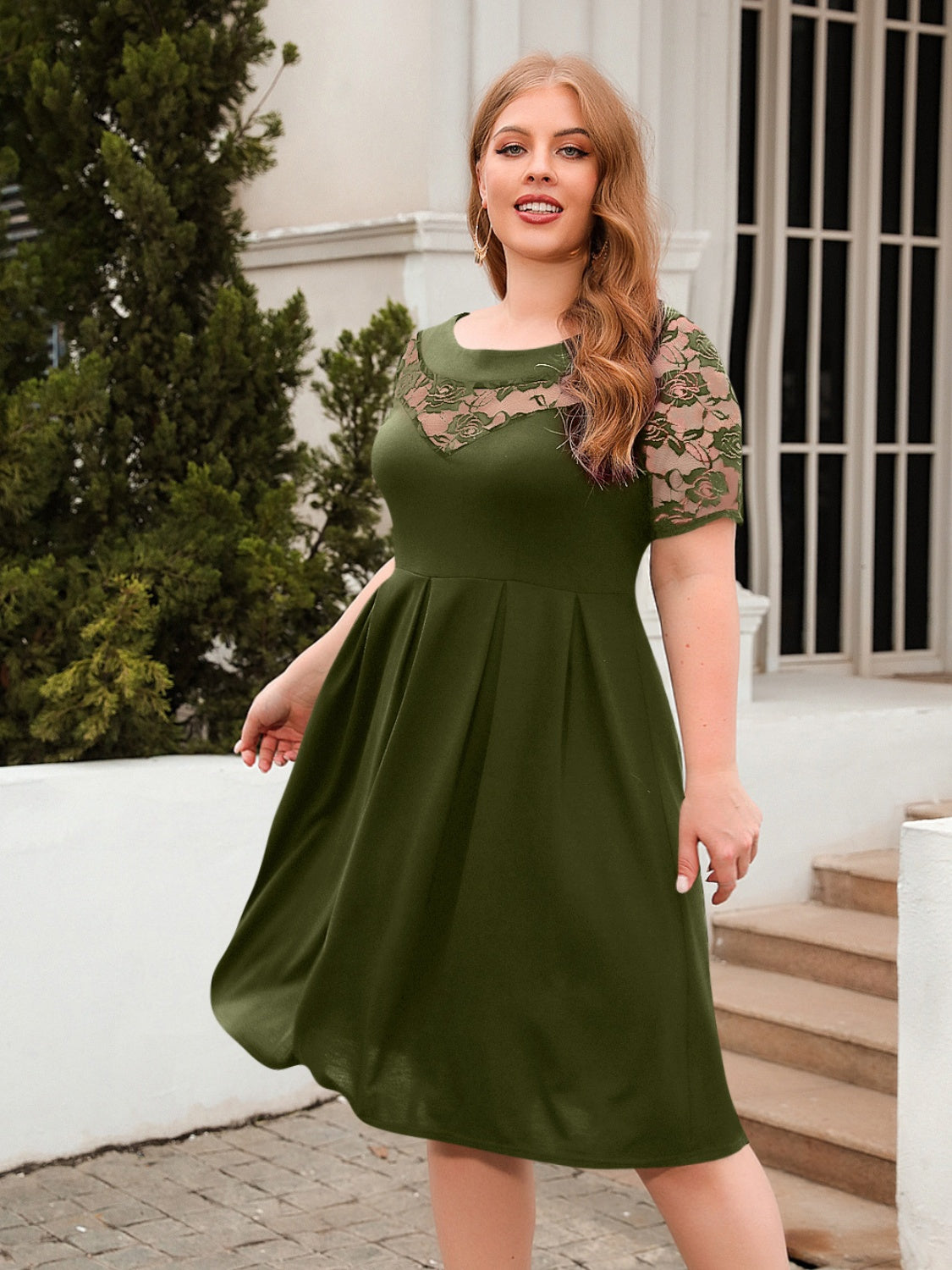Plus size green ruched round neck dress with lace short sleeves worn outdoors