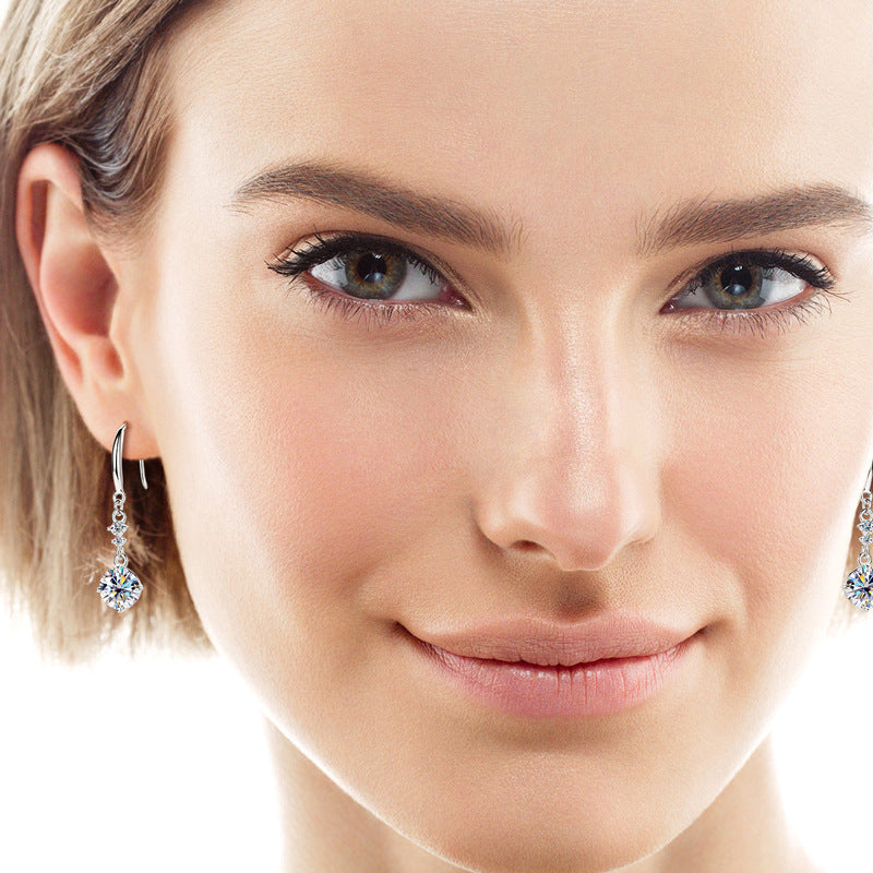 Close-up of woman wearing 2 carat moissanite sterling silver earrings with sparkling round stones