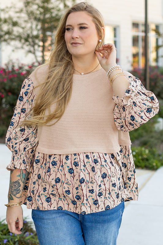 Plus size woman wearing a beige faux two piece knit blouse with floral patterned sleeves and hem