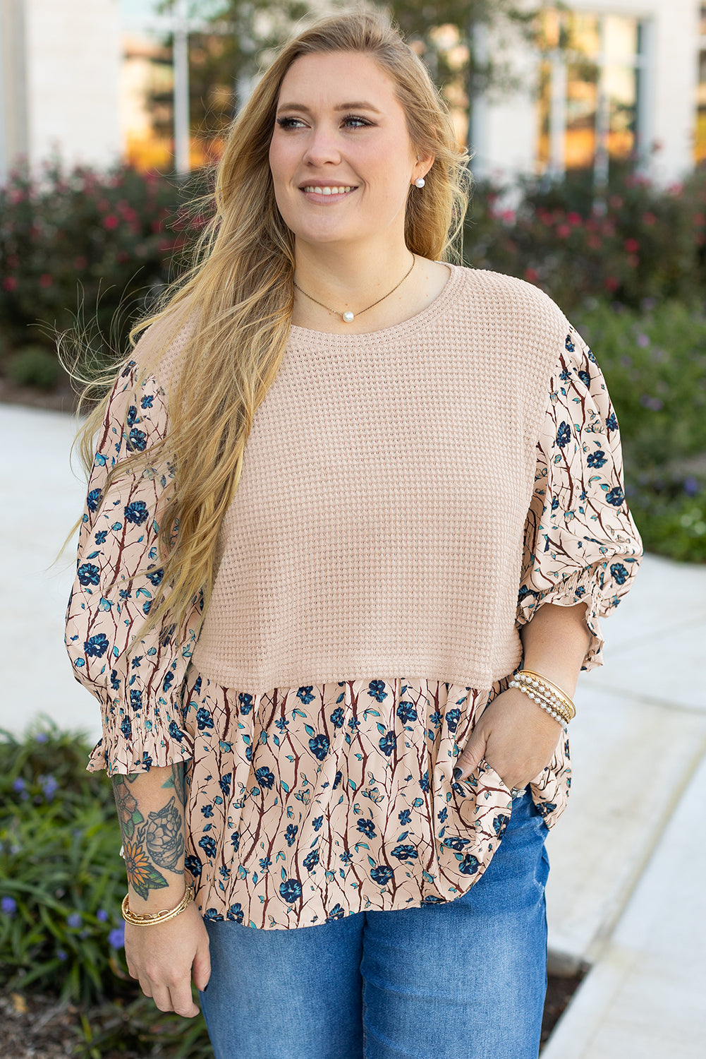 Plus size woman wearing beige faux two piece knit blouse with floral sleeves and ruffle hem