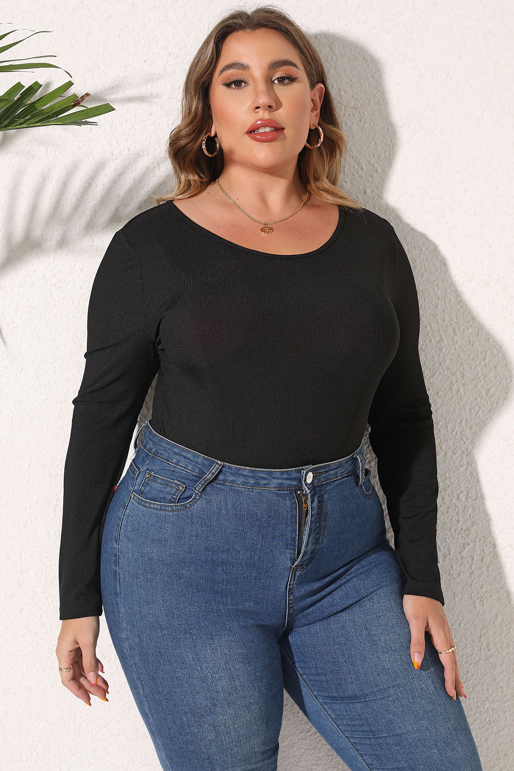black plus size bodysuit with long sleeves and scoop neckline worn with blue jeans