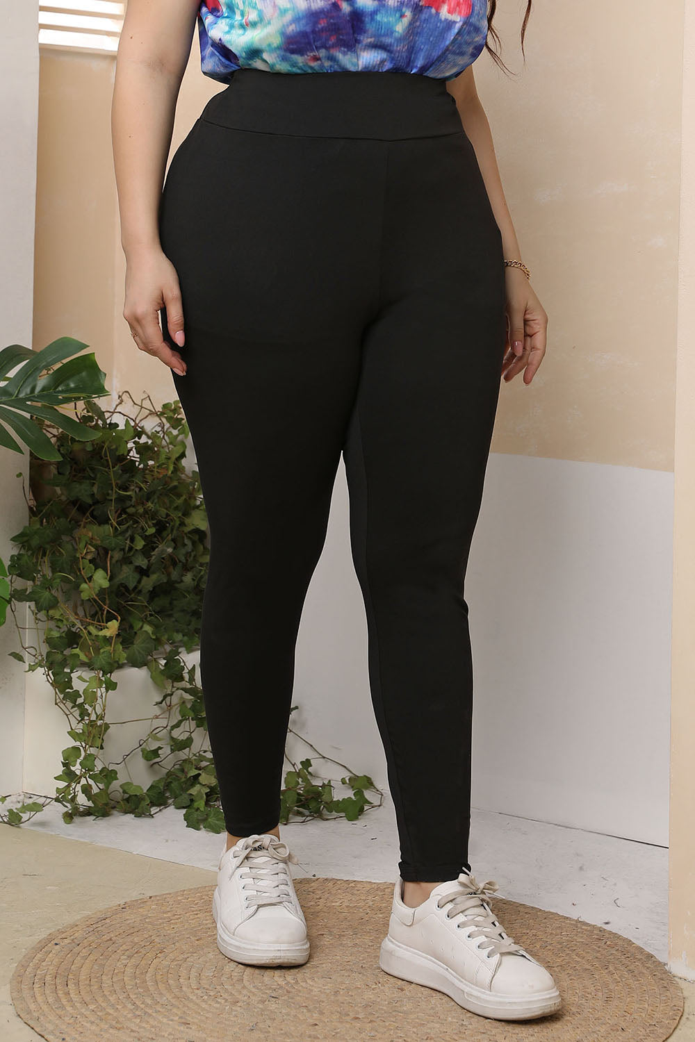 Trendsi black plus size skinny pants worn with white sneakers and a colorful top