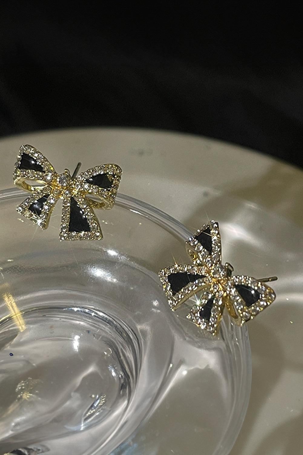 Elegant black rhinestone bow earrings with gold-tone accents by kjplussizefashion displayed on clear glass