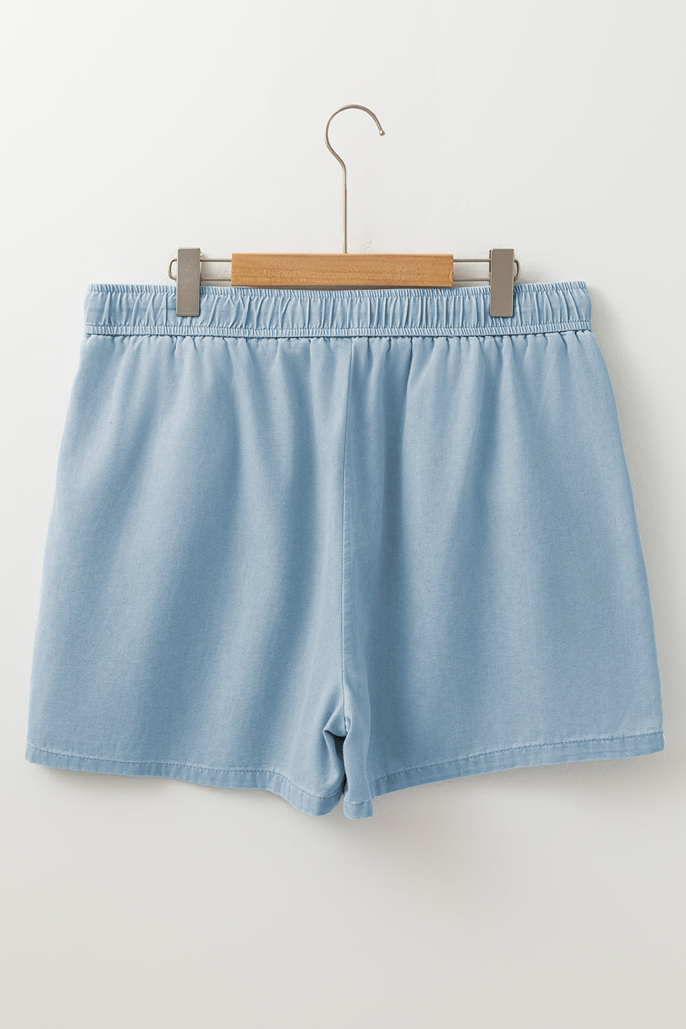 Light blue elastic waist plus size summer shorts hanging on wooden hanger