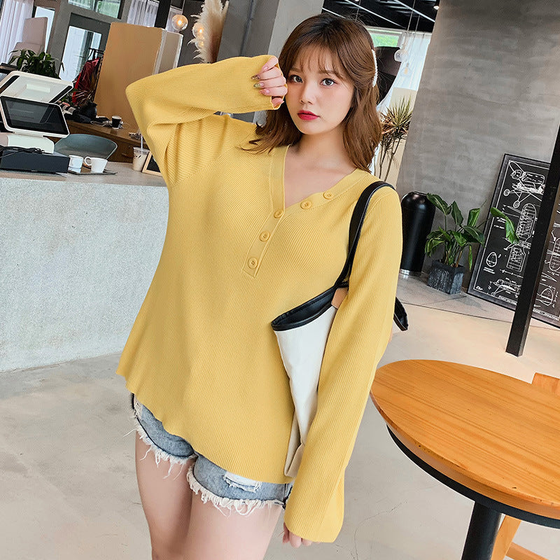 Woman wearing a yellow button v-neck knit sweater for curvy women styled with denim shorts in a modern cafe