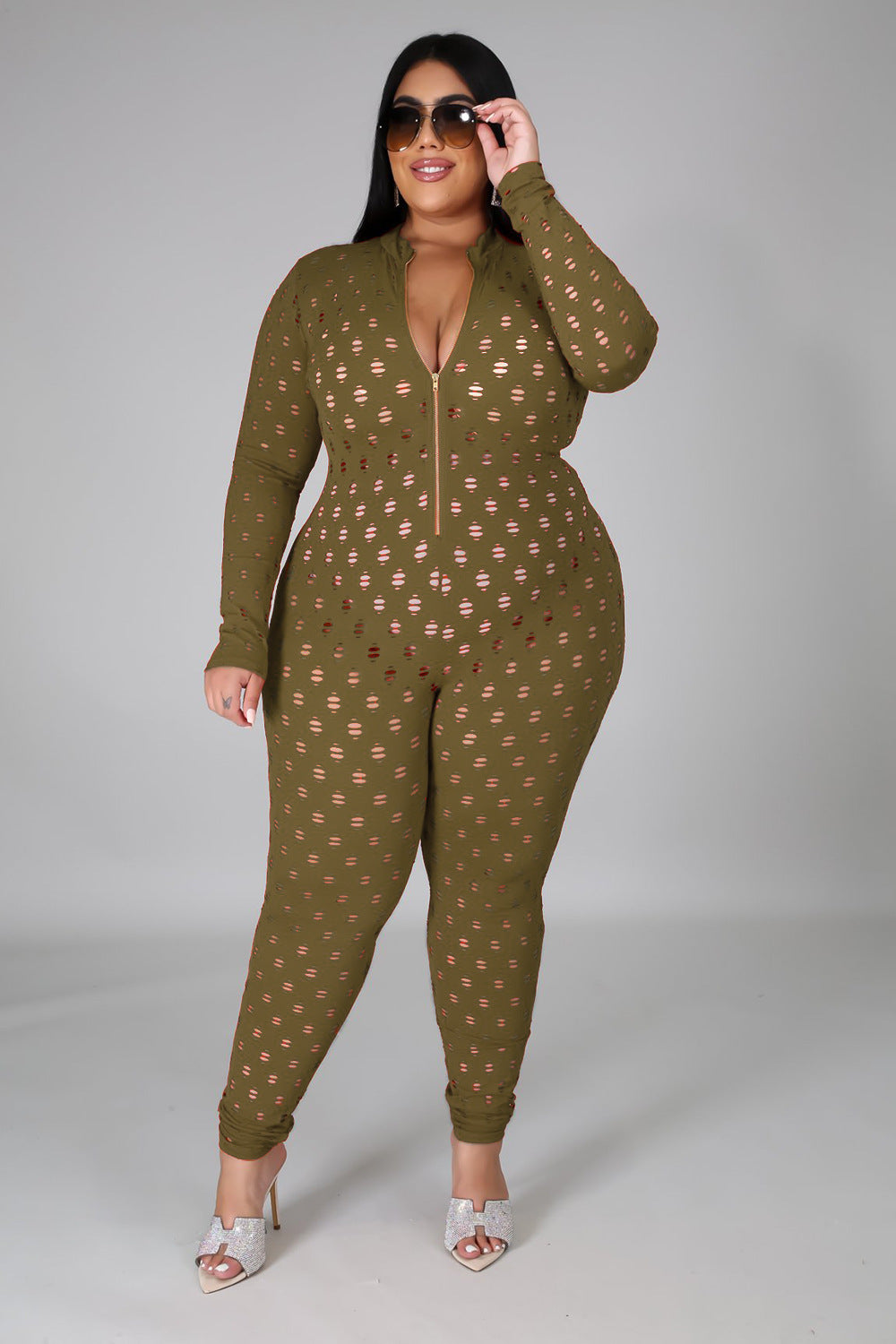 Curvy woman wearing olive green curvy women zip front jumpsuit with cut-out details and white heels