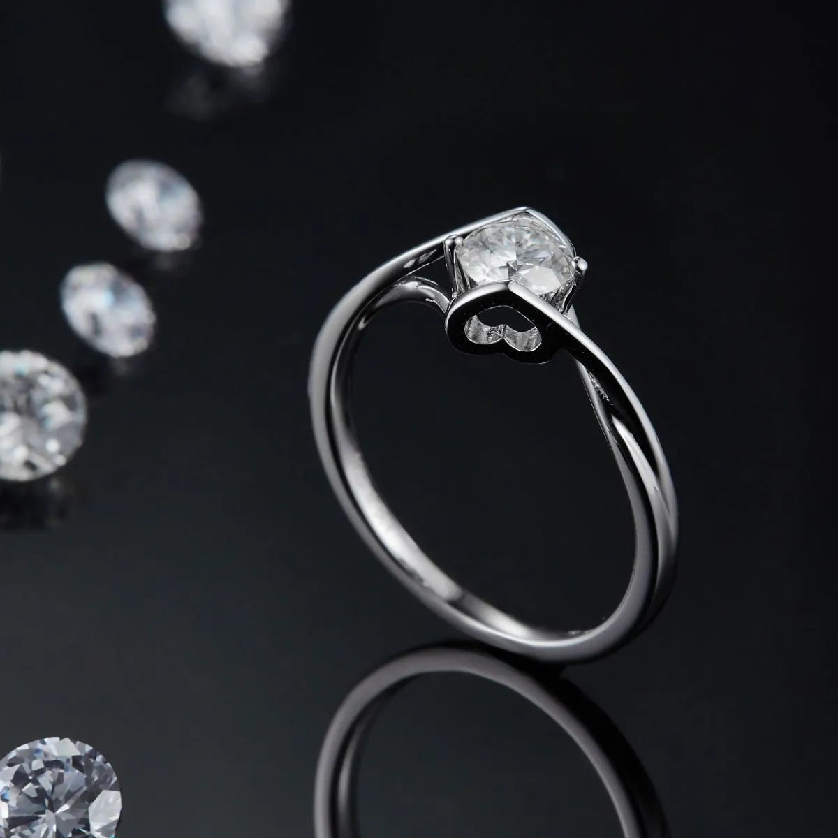 Elegant moissanite sterling silver ring with a sparkling center stone on a reflective black surface