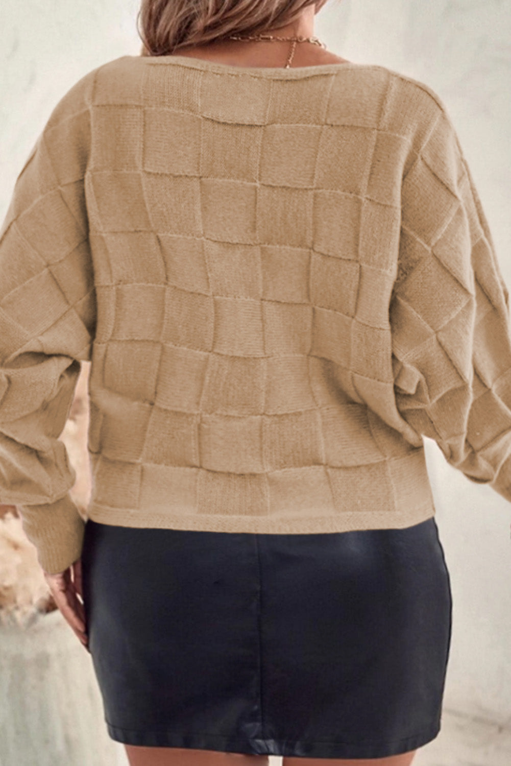 Back view of plus size beige sweater for women with textured square pattern worn with black skirt