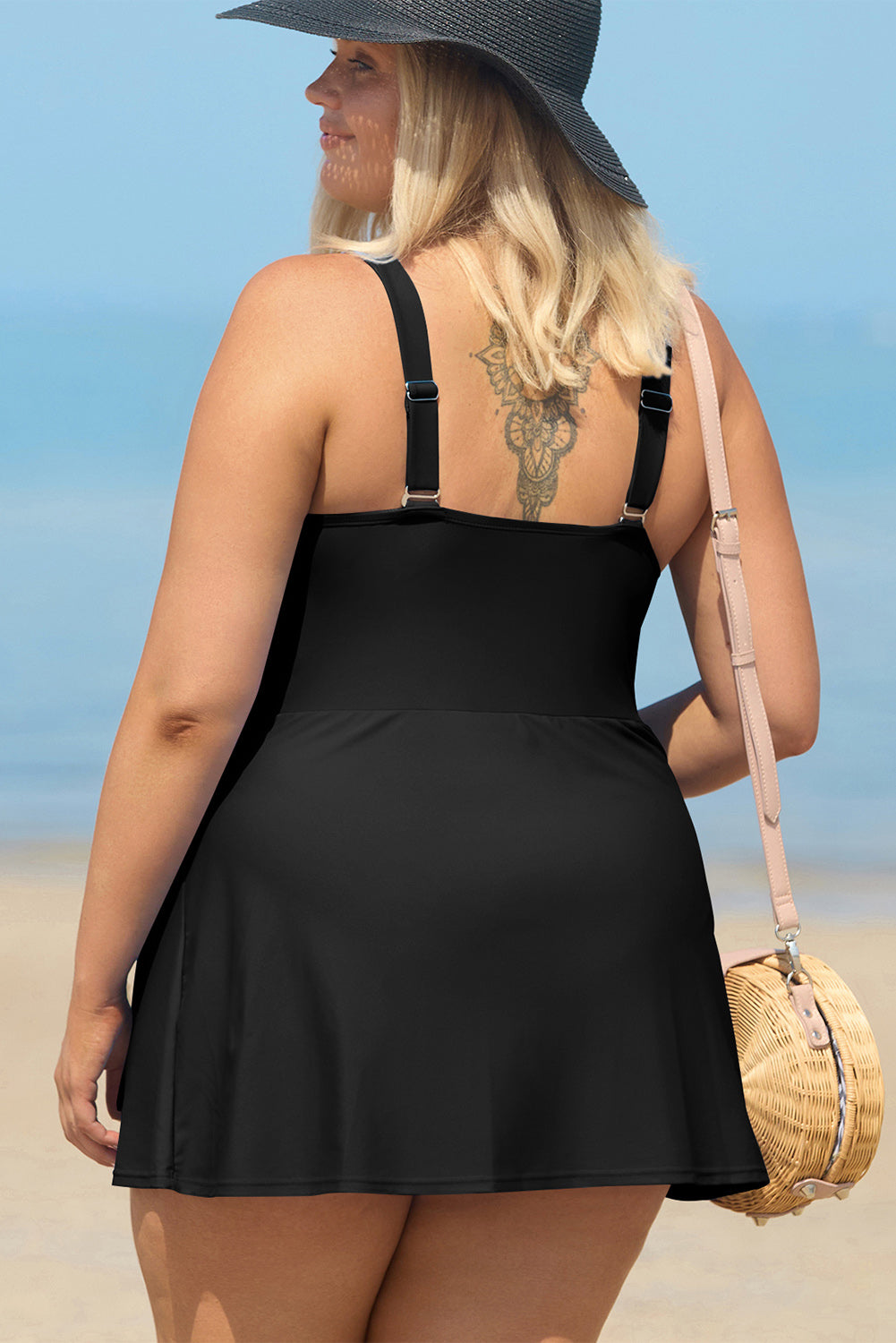 Plus size black one piece swimsuit with adjustable straps worn by woman at the beach