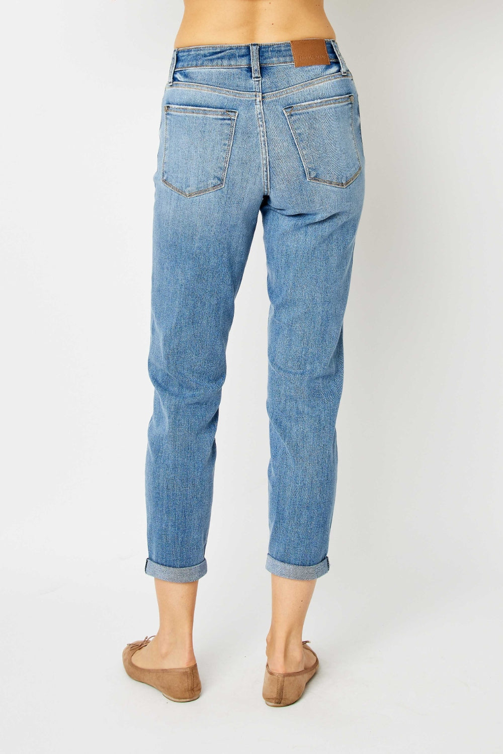 Back view of plus size cuffed hem jeans in light blue denim worn by a model with rolled cuffs