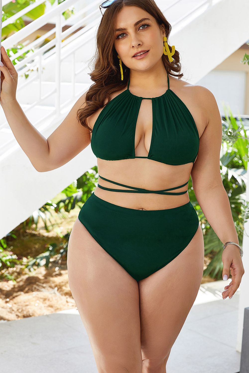 Plus size cutout bikini set in dark green with halter neck and wrap-around straps on model outdoors