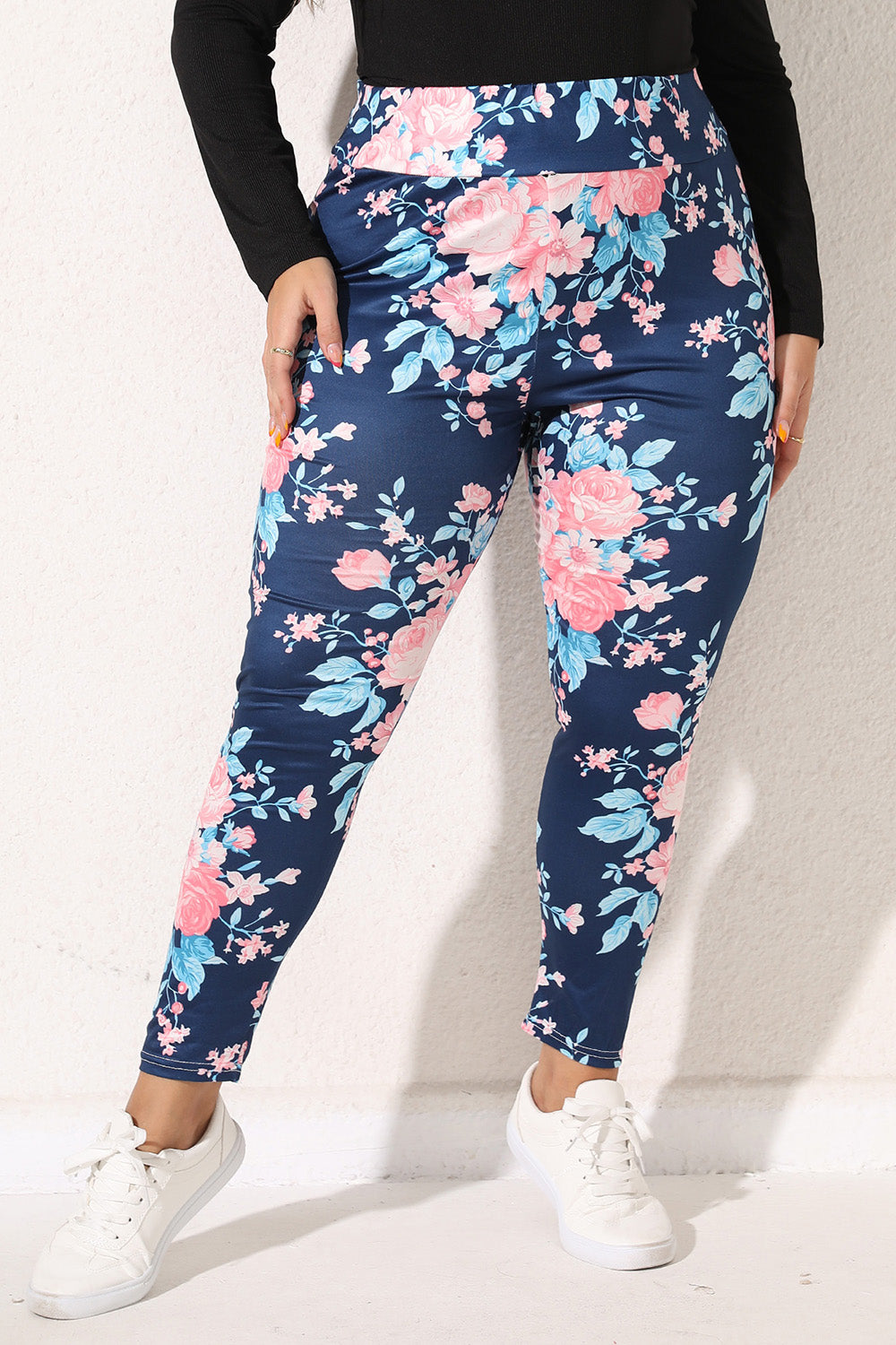 Plus size floral leggings in navy blue with pink and light blue flowers worn with white sneakers