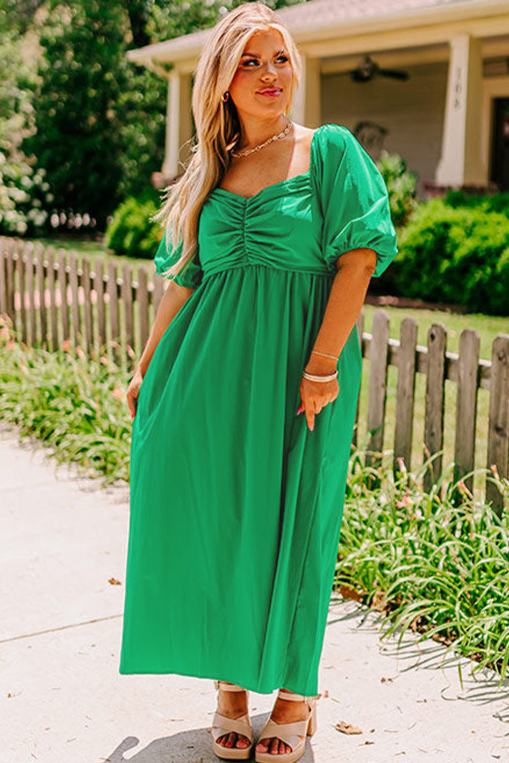 Plus size green puff sleeve dress with ruched bust and flowing maxi skirt worn outdoors