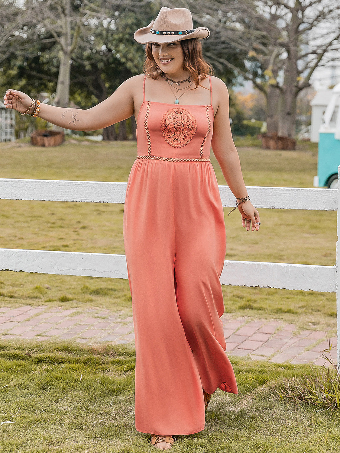 Trendsi plus size lace jumpsuit in coral with spaghetti straps worn outdoors with a hat
