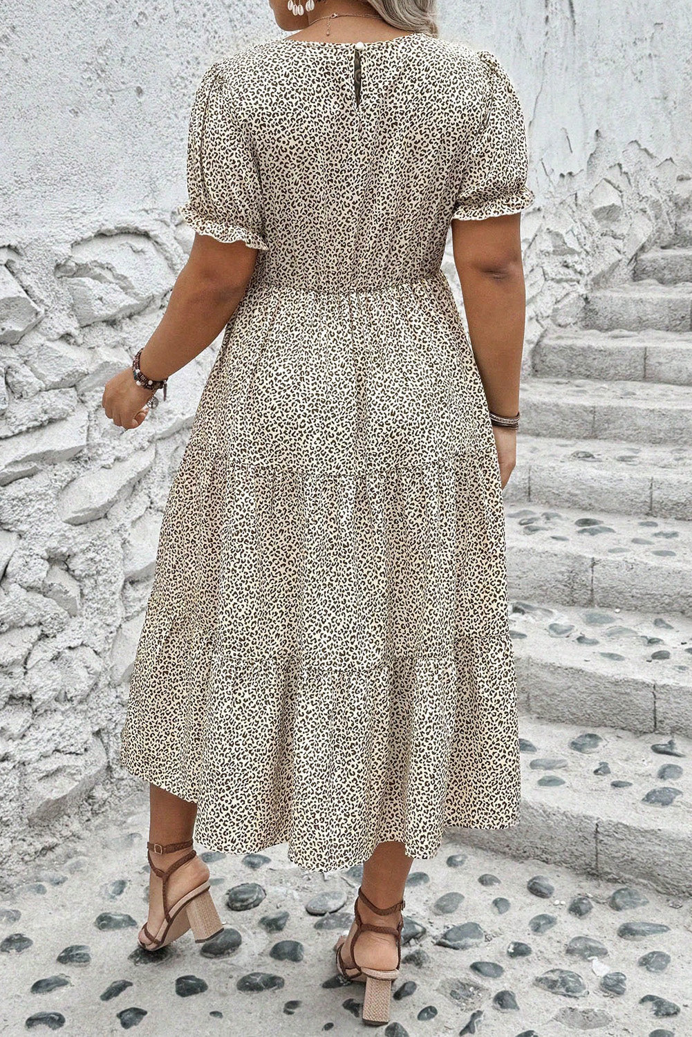 Back view of plus size leopard print dress with short sleeves and tiered midi skirt on woman