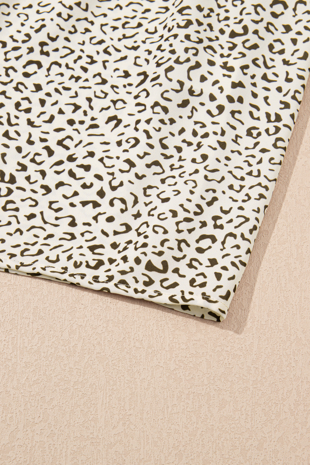 Close-up of plus size leopard print dress fabric with brown and black spots on white background
