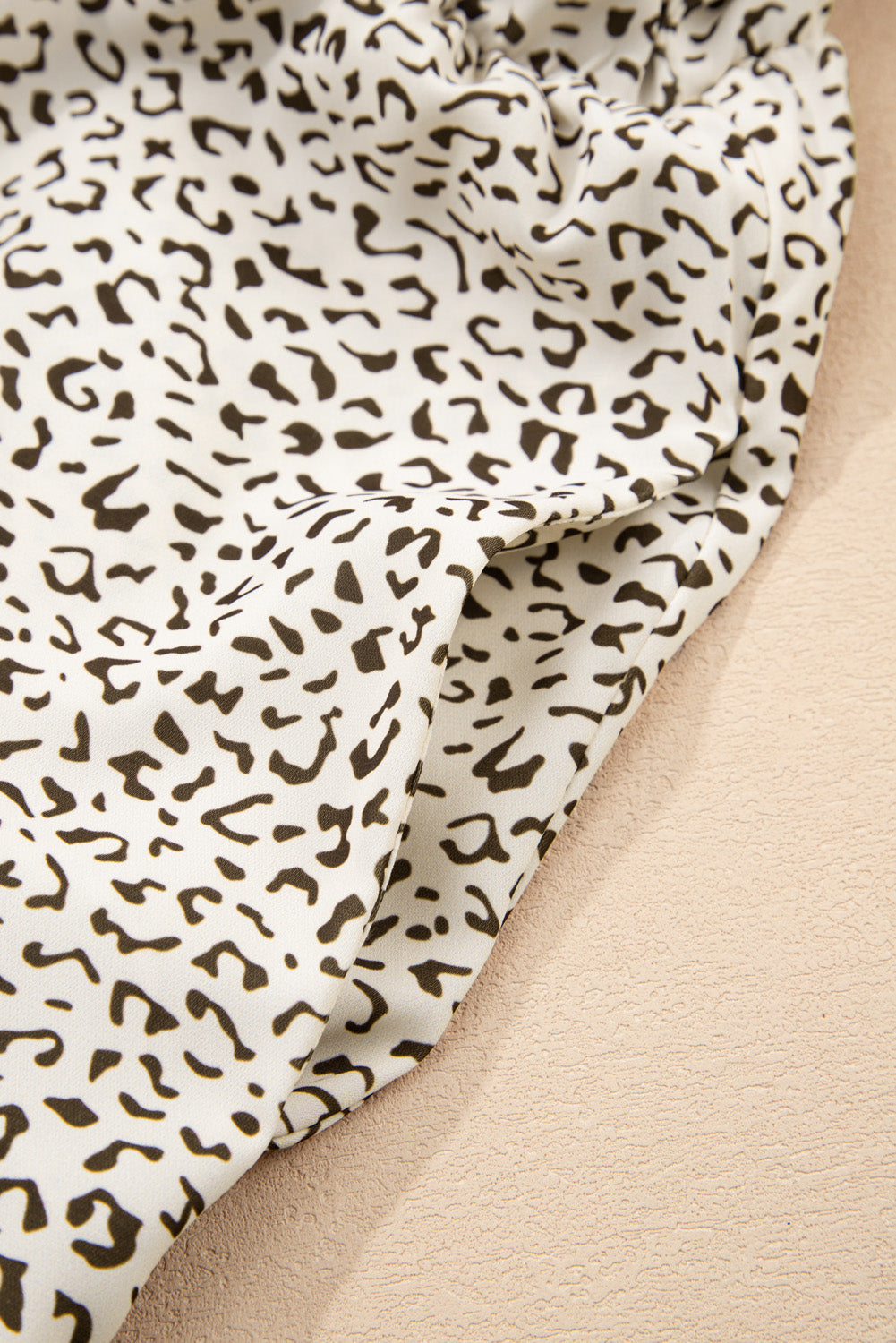 Close-up of kjplussizefashion plus size leopard print dress fabric with black spots on white background