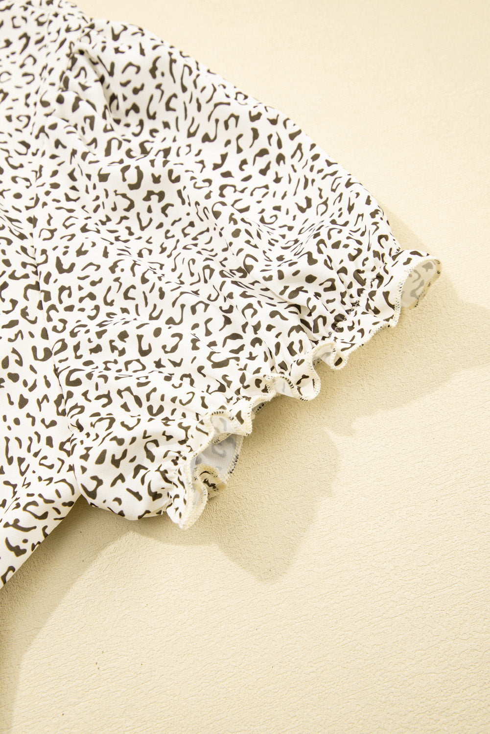 Close-up of a ruffled sleeve on a white plus size leopard print dress from kjplussizefashion