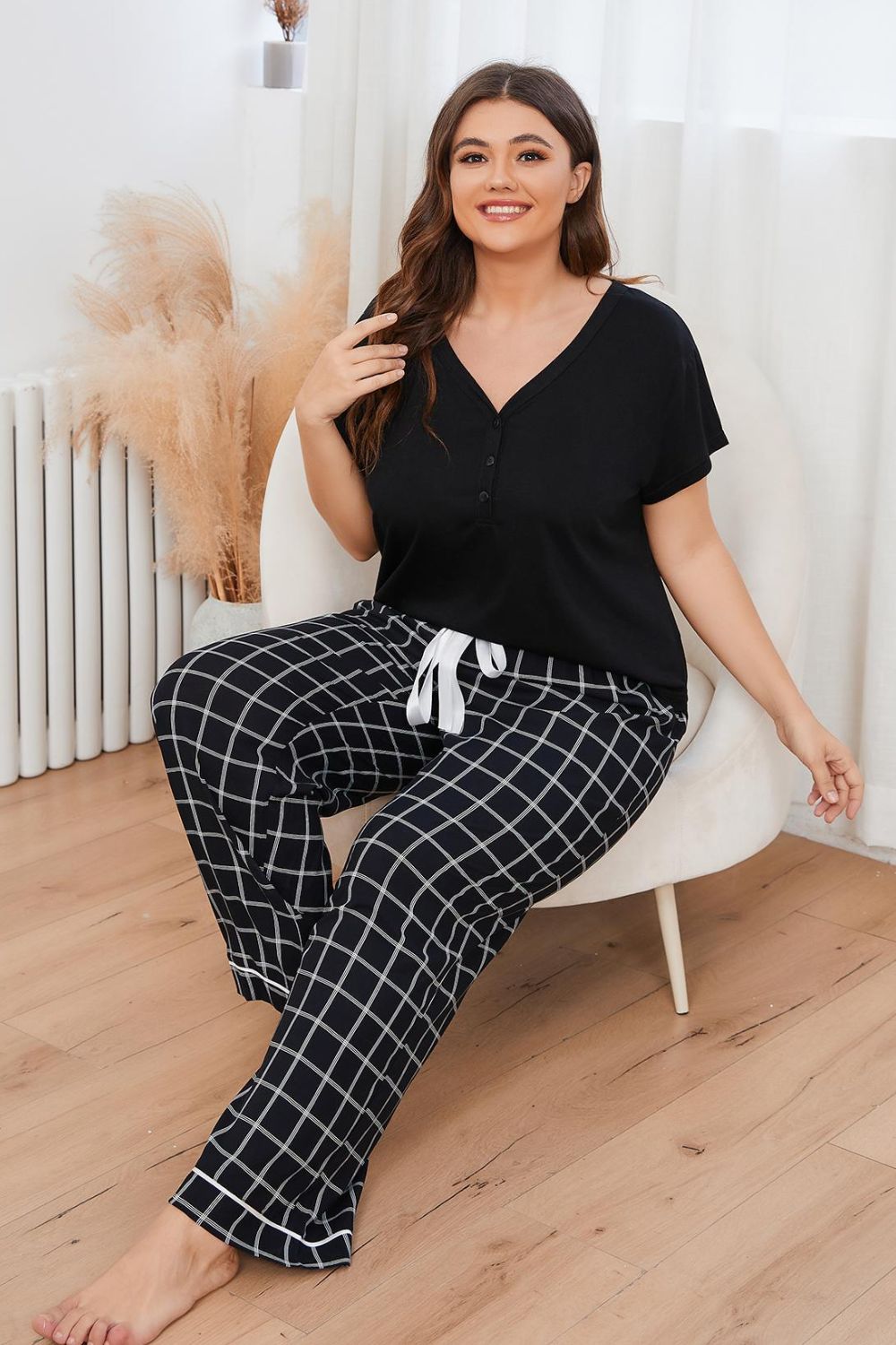 Plus size loungewear set with black short sleeve top and black and white checkered pants with drawstring