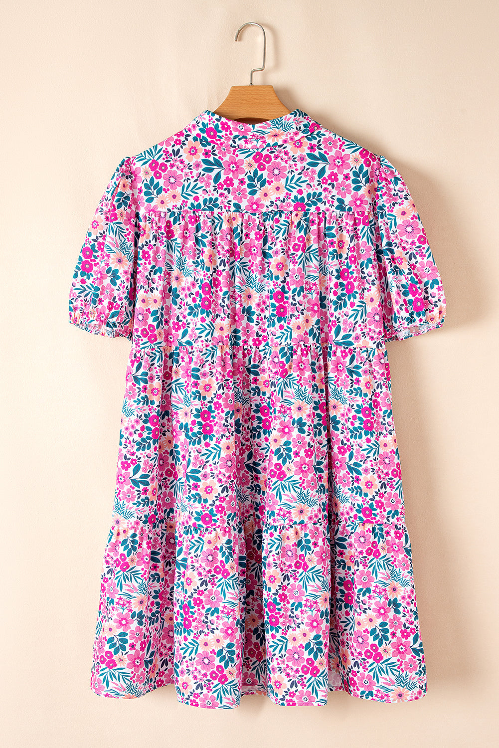 Pink plus size floral A-line dress with short puff sleeves and half button detail hanging on wooden hanger