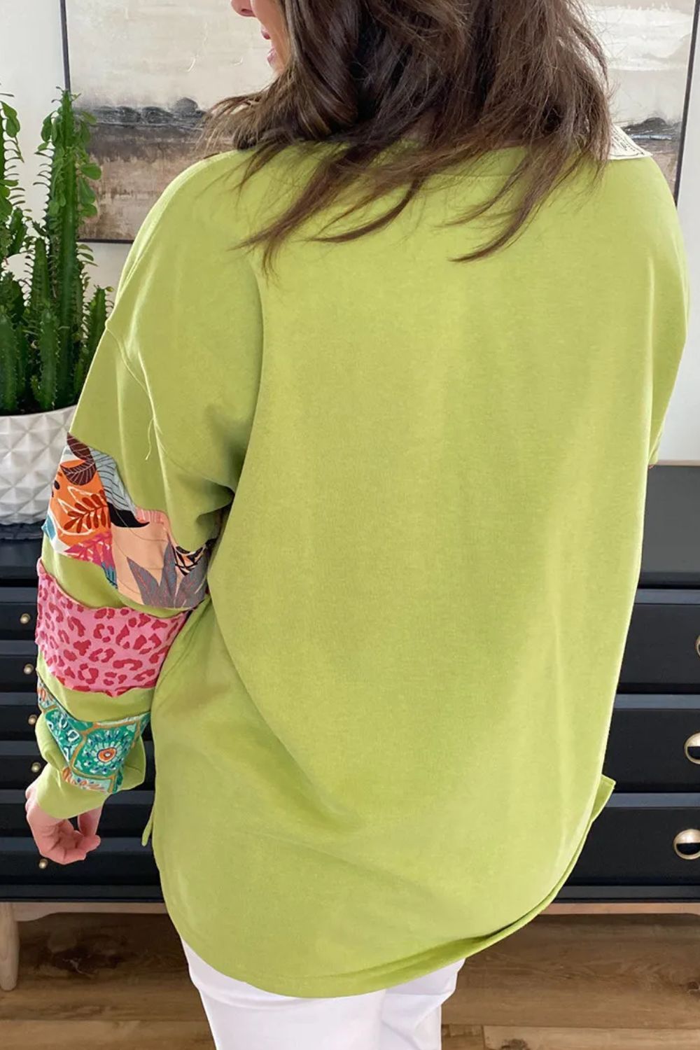Plus size sweatshirt with solid green back and colorful printed long sleeves featuring animal and floral patterns
