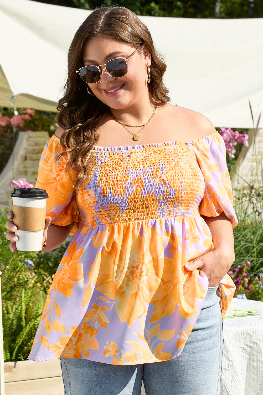 Plus size purple floral blouse with orange flowers and off-shoulder design worn with jeans