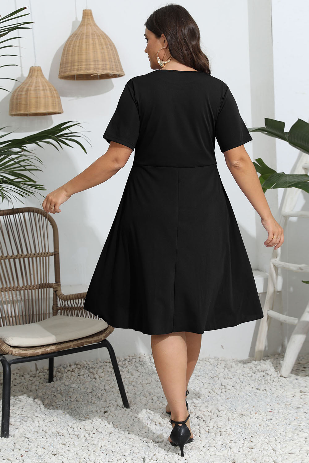 Trendsi plus size round neck openwork dress in black worn by model standing indoors