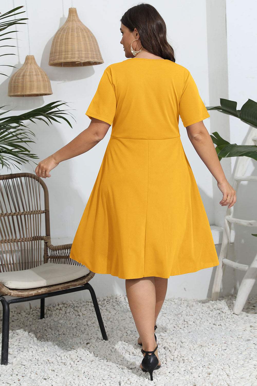 Back view of a woman wearing a plus size round neck openwork dress in yellow with short sleeves