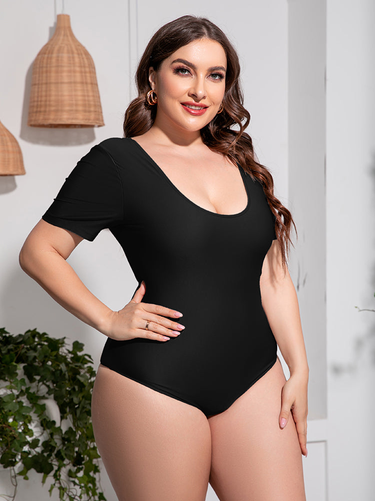 Trendsi plus size scoop neck swimsuit in black with short sleeves on a smiling model indoors