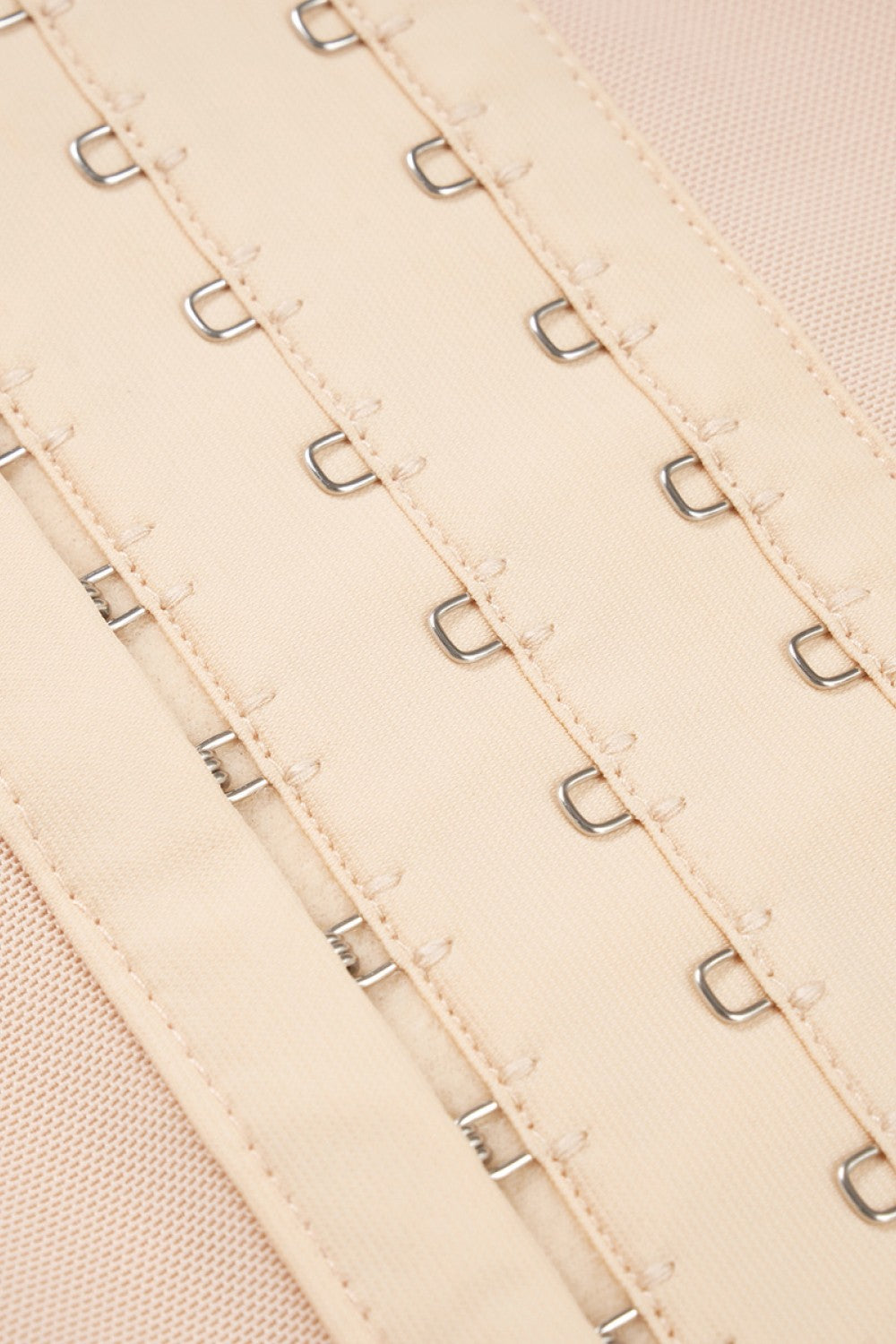 Close-up of beige plus size shaping bodysuit hook and eye closures for adjustable fit