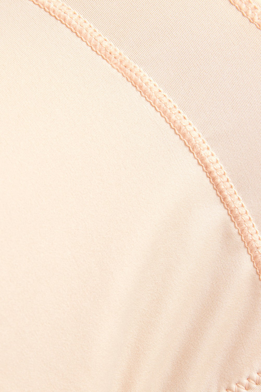 Close-up view of beige fabric with stitching detail for plus size shaping shorts by Trendsi