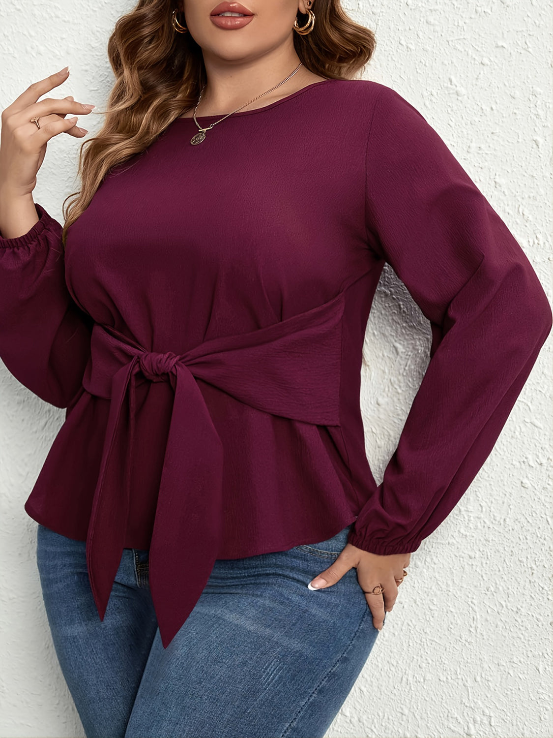Plus size tie front blouse in deep purple with long sleeves and casual fit paired with blue jeans