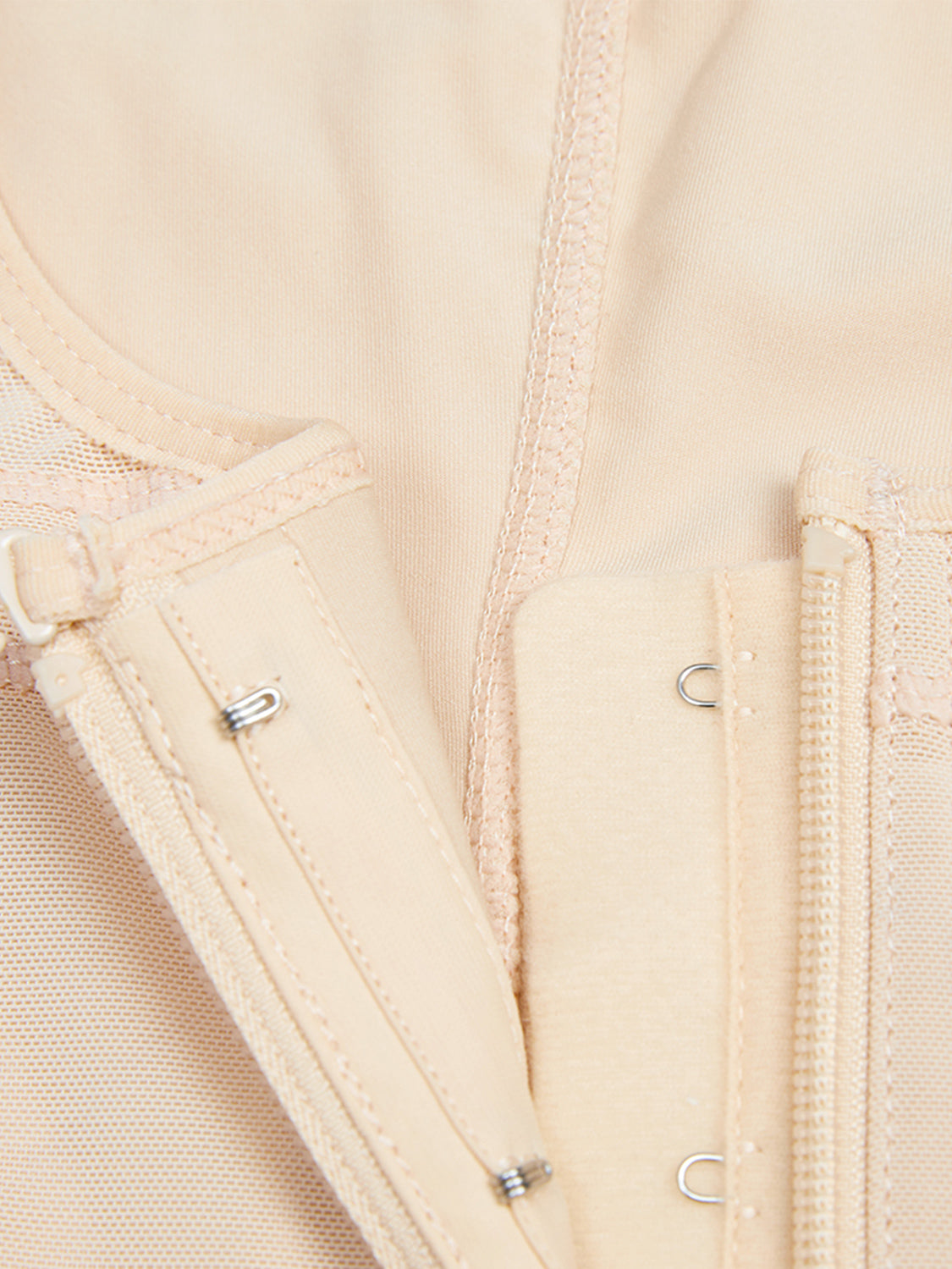 Close-up of beige plus size zip up shapewear detailing the zipper and hook closures