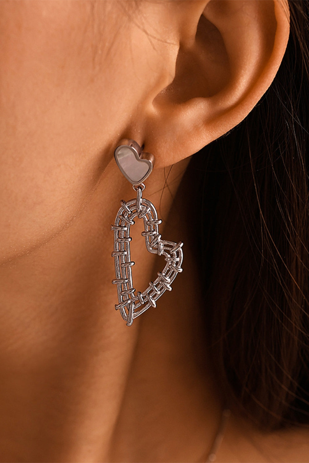 Close-up of a stainless steel heart jewelry set earring worn on ear with intricate linked heart design