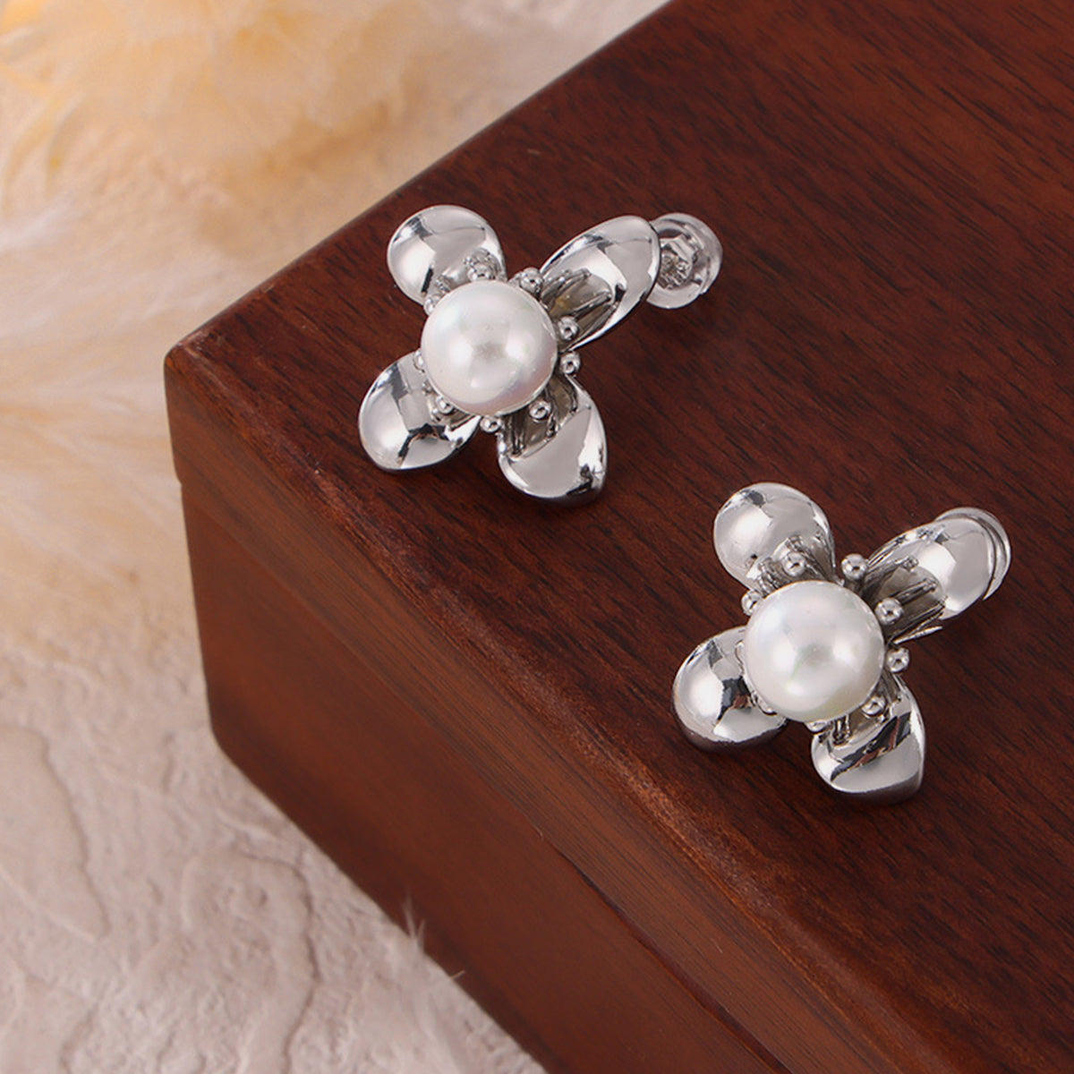 Trendsi synthetic pearl titanium earrings with silver-tone floral design on wooden surface
