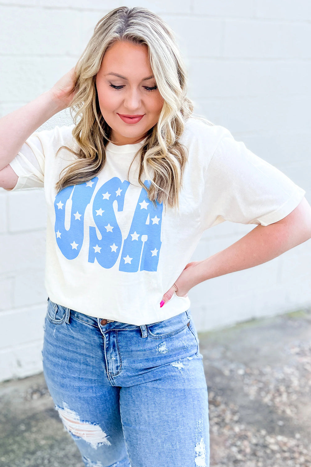 Woman wearing sky blue USA graphic plus size tee paired with distressed blue jeans outdoors