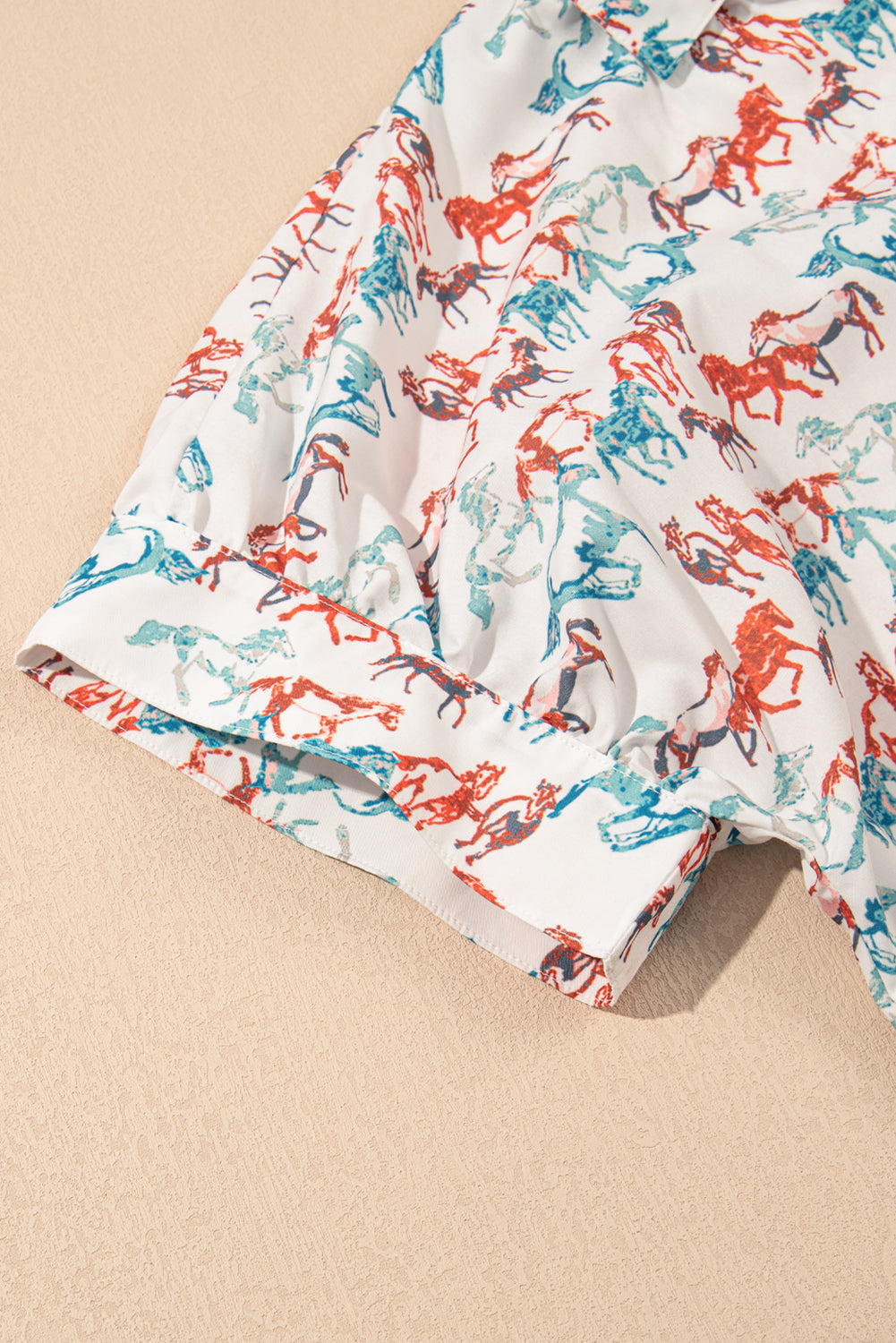 Close-up of split neck western plus size top with colorful horse print on white fabric