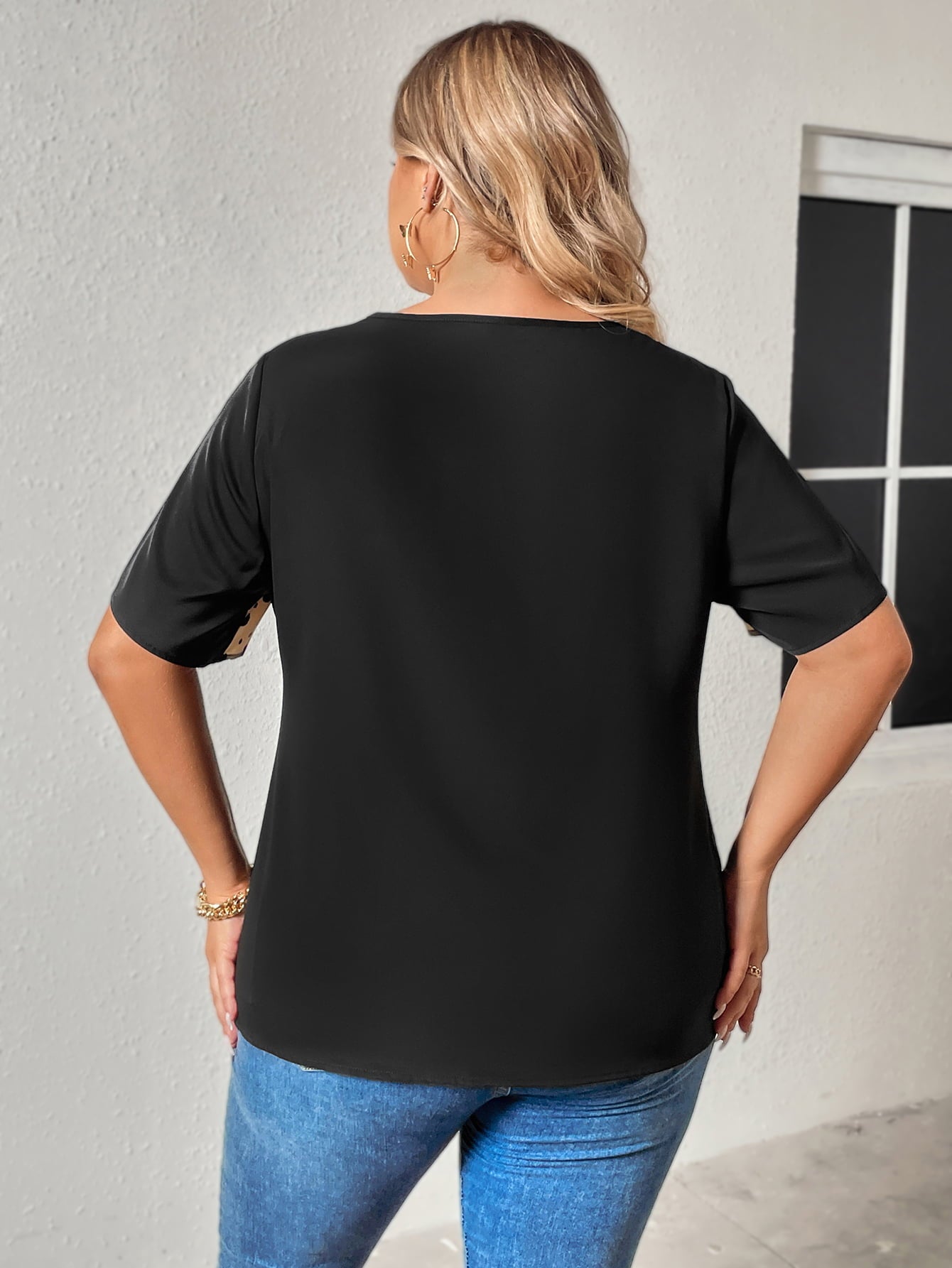 Back view of a black v neck raglan sleeve top for plus size paired with blue jeans