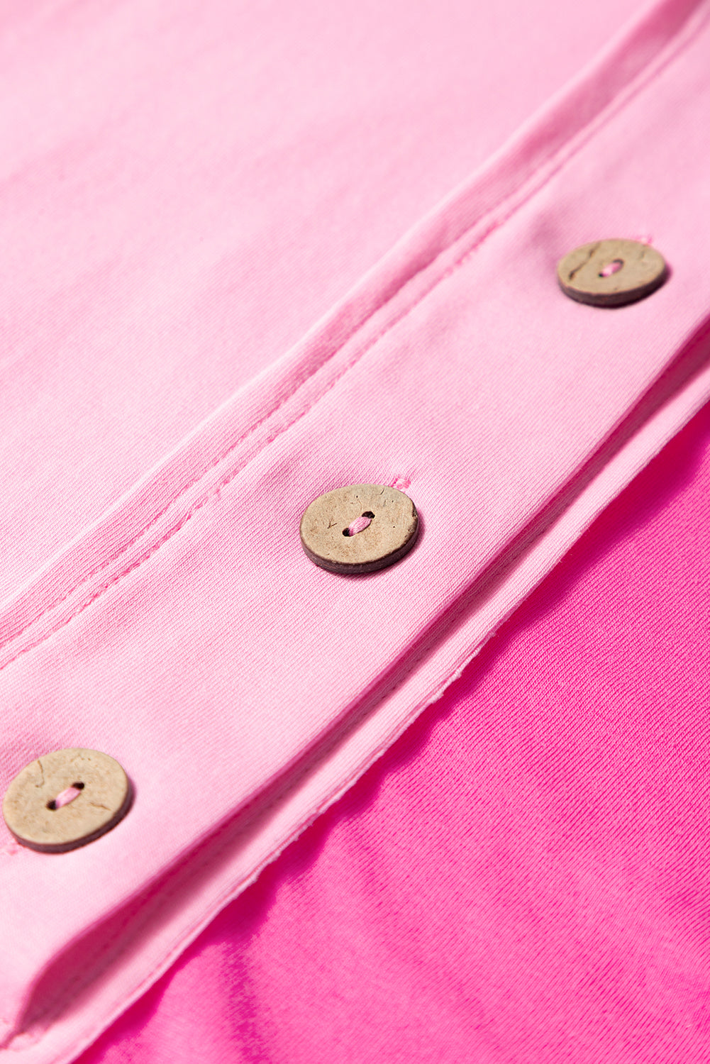 Close-up of bright pink short sleeve top for curvy women with wooden buttons and soft fabric