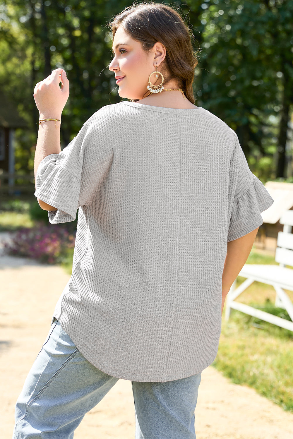 Plus size model wearing a light grey ruffle sleeve blouse by kjplussizefashion outdoors