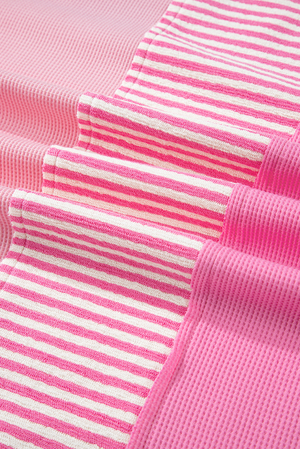 Close-up of pink stripe patchwork fabric on plus size summer shirt showing textured and striped patterns
