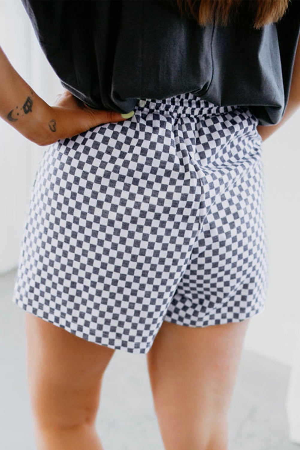 Plus size checkerboard shorts in black and white worn by a woman with a black top