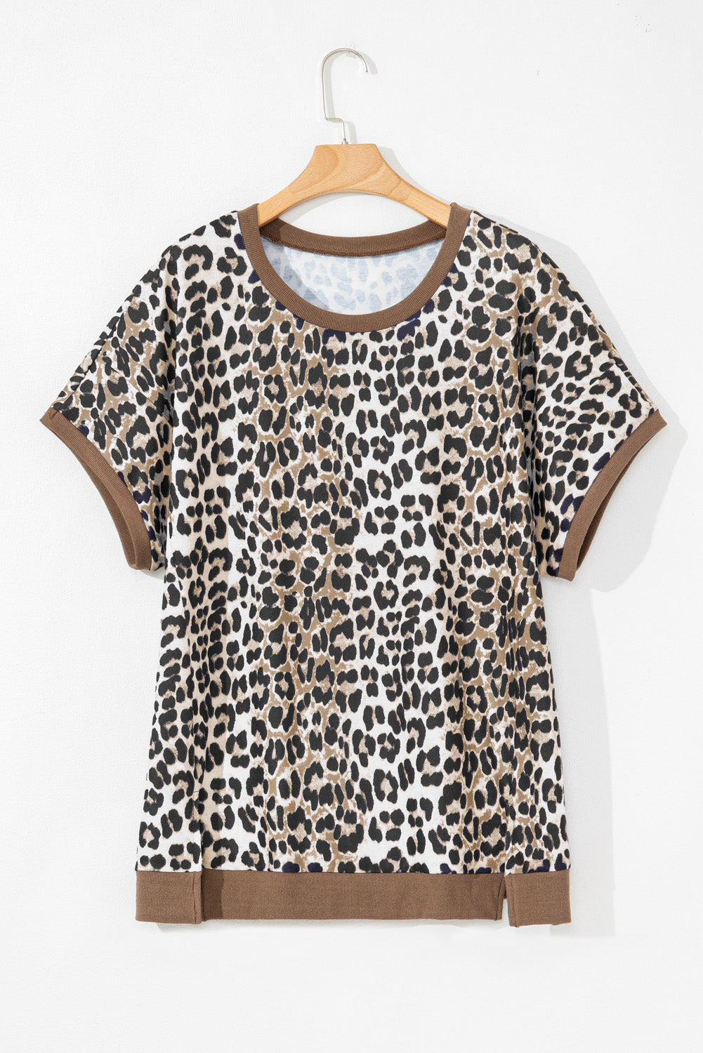 Plus size leopard print top with brown trim on sleeves and hem hanging on wooden hanger