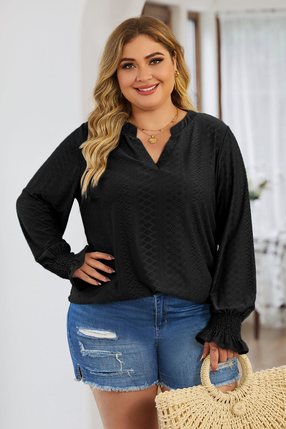 Plus size trendy blouse for women in black with textured fabric and long sleeves paired with denim shorts
