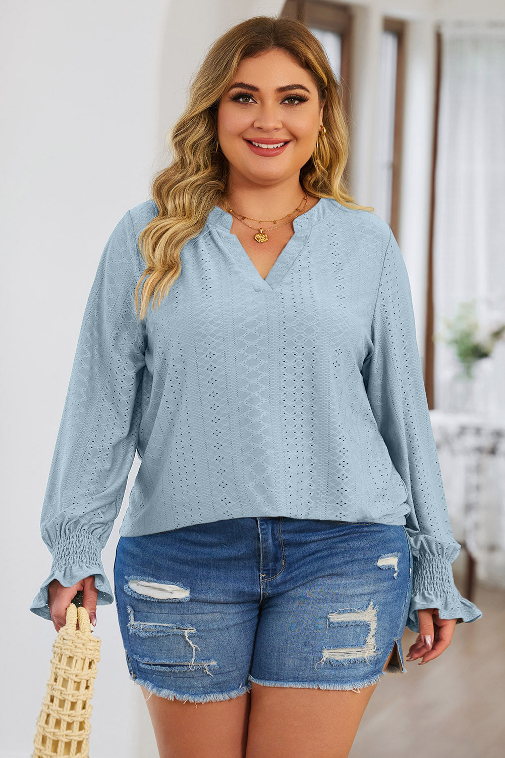 Plus size trendy blouse for women in light blue eyelet fabric with long sleeves and ruffled cuffs