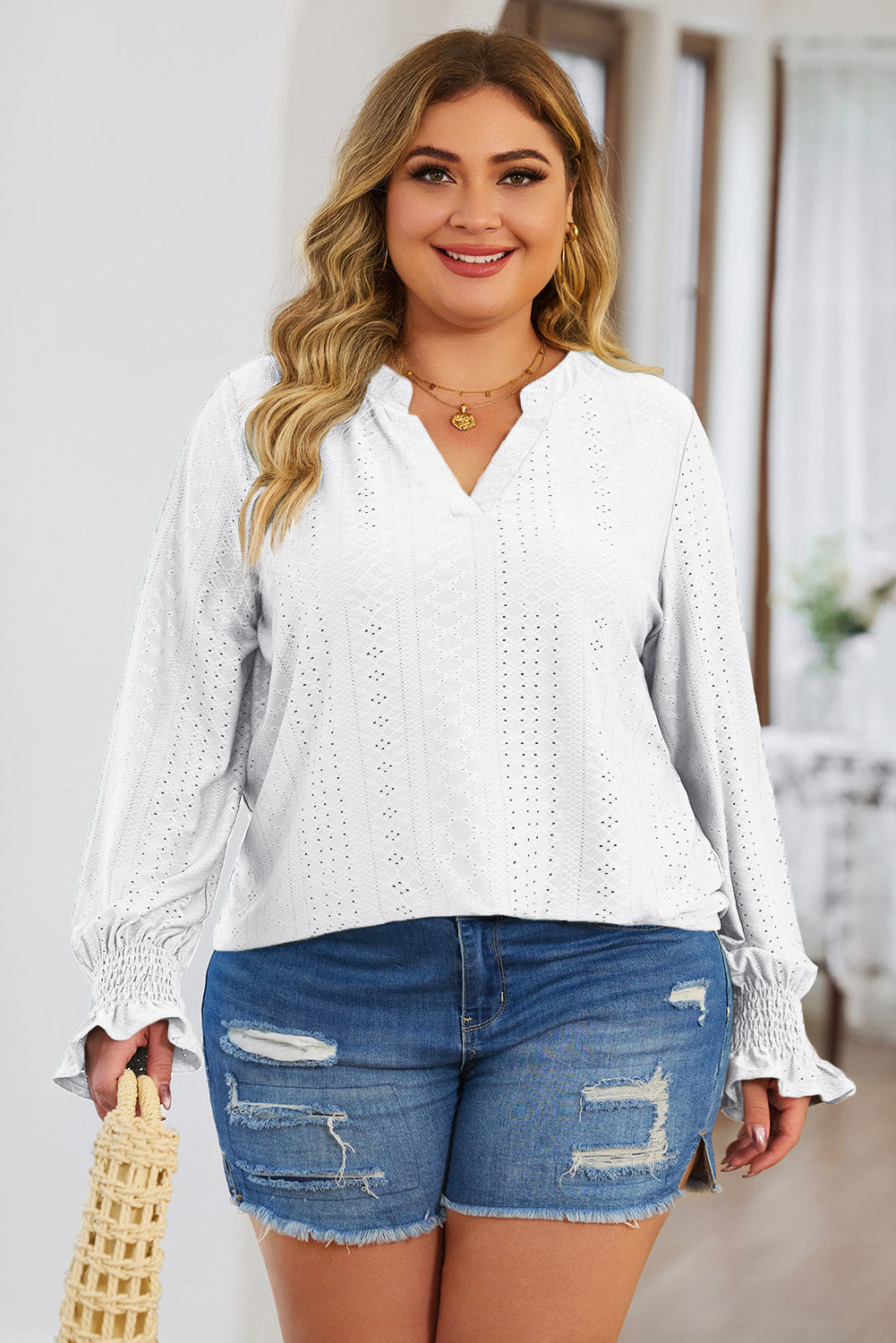 Plus size trendy blouse for women in white with eyelet details worn with distressed denim shorts