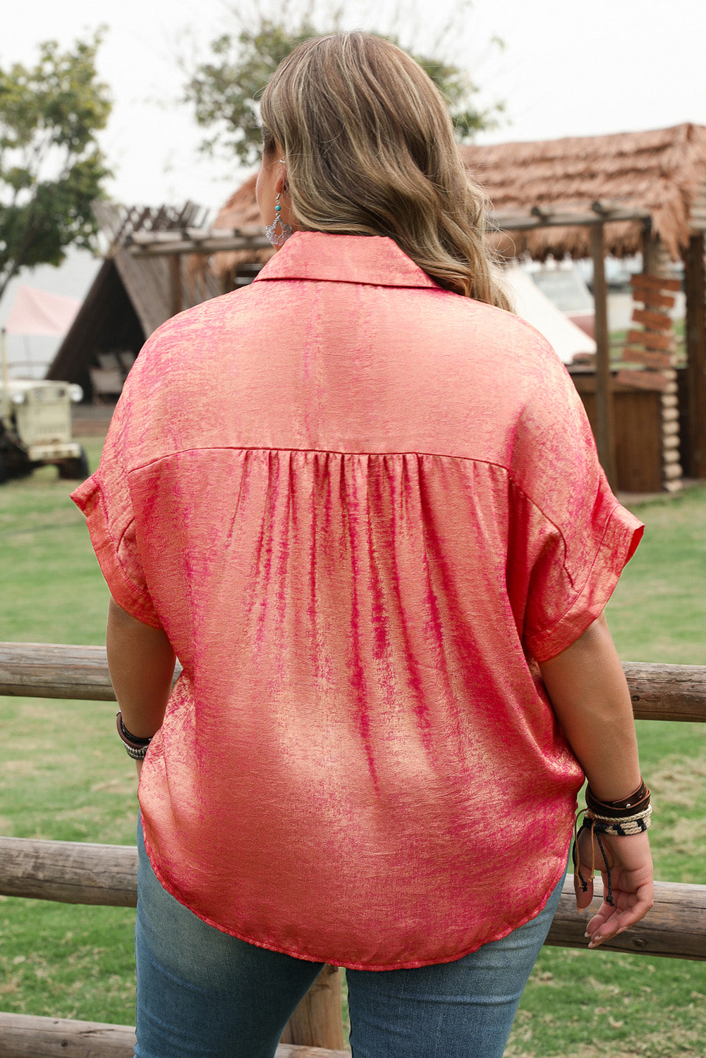Back view of a woman wearing a rose red plus size metallic shirt with short sleeves outdoors