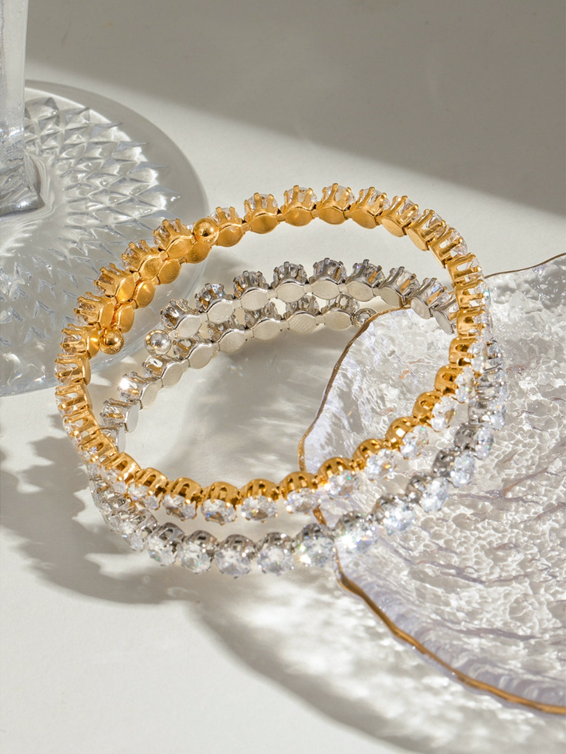 Stainless steel zircon bracelet in gold and silver tones displayed on decorative glass surfaces