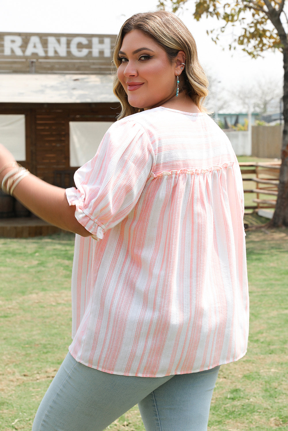 Plus size tassel tie frilled sleeve top for curvy women in light pink and white stripes outdoors