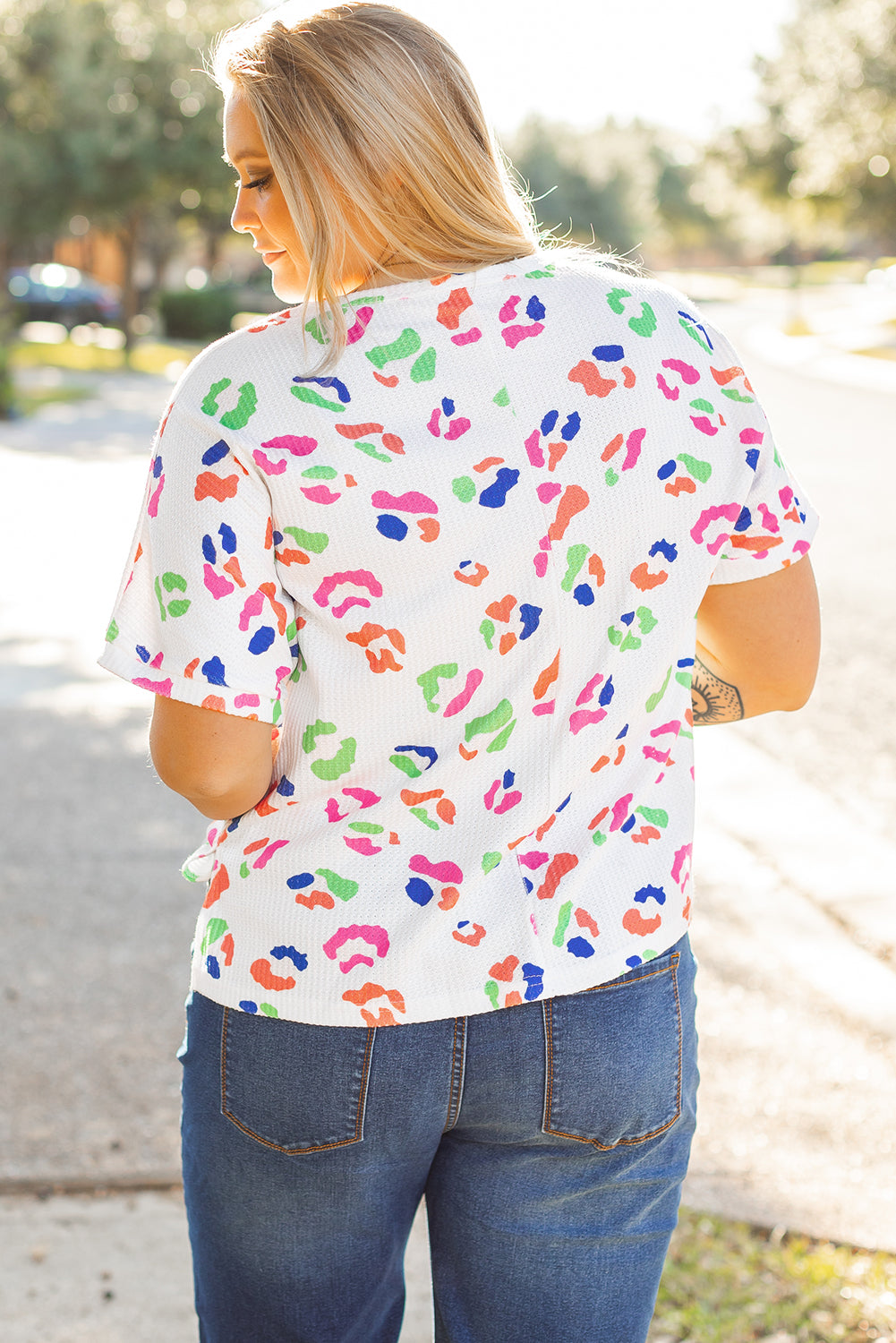 Plus size woman wearing a white multicolor leopard top for women with short sleeves and relaxed fit